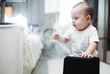 Little baby looks at the humidifier. Moisture in the house concept