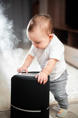 Little baby looks at the humidifier. Moisture in the house concept