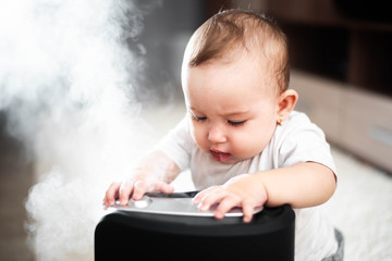 Little baby looks at the humidifier. Moisture in the house concept