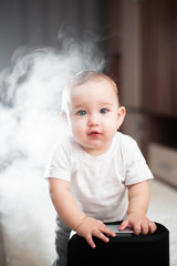 Little baby looks at the humidifier. Moisture in the house concept