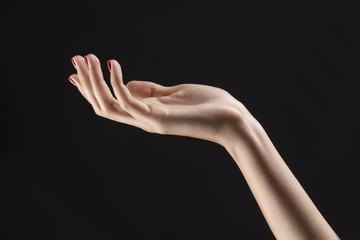 Fototapeta premium Closeup of beautiful woman hand with red manicure on the nails. Cream for palms, manicure and beauty treatment. Elegant and graceful arm with slender graceful fingers