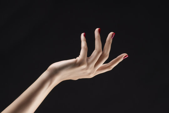 Closeup of beautiful woman hand with red manicure on the nails. Cream for palms, manicure and beauty treatment. Elegant and graceful arm with slender graceful fingers