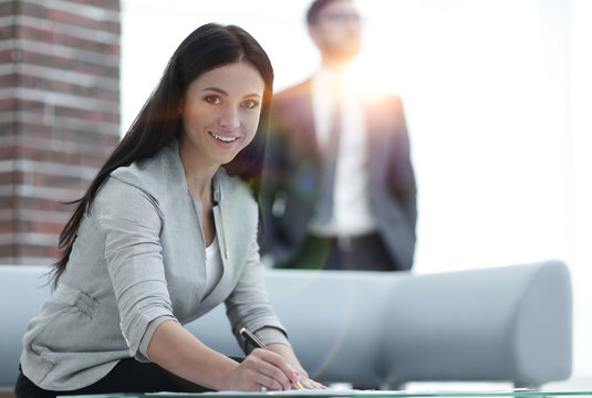 business woman signs documents in a modern office.