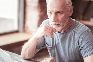 Contemplations. Close up of elderly man being thoughtful while looking away and keeping his hand under his chin