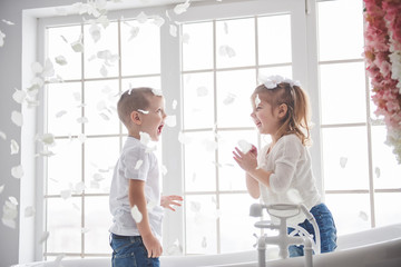 Child playing with rose petals in home bathroom. Little girl and boy fawing fun and joy together. The concept of childhood and the realization of dreams, fantasy, imagination