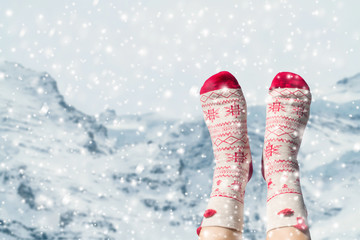 Women's feet in Christmas socks on the Swiss Alps background. Winter concept.
