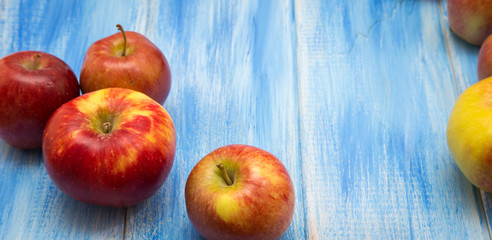 Apples on a blue wooden background. Red and yellow farm apples.