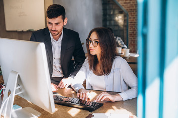 Working on creative project together. Two confident business people in casual wear sitting together at the table and discussing something. startup
