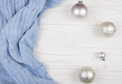 Light blue wool fabric and Christmas balls of a silver color on a white wooden background (copy space for your text, top view) as a New Year or Christmas background