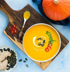Kürbissuppe lecker angerichtet und bereit zum essen auf holzbrett auf hellem hintergrund bei tageslicht von oben fotografiert