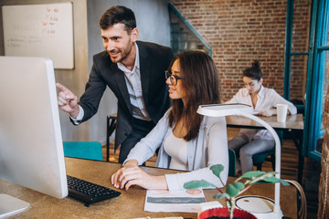 Working on creative project together. Two confident business people in casual wear sitting together at the table and discussing something. startup