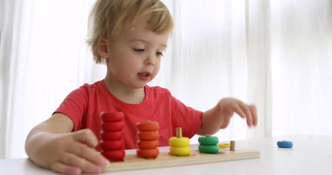 Kid playing with wooden developing puzzle toys. Educational child toys for preschool and kindergarten