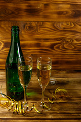 Opened champagne bottle and two glasses of champagne on wooden table