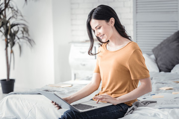 Online communication. Cheerful female sitting in semi position and bowing head while doing task with pleasure © Viacheslav Yakobchuk