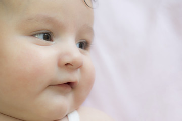 babyhood, childhood and people concept - happy baby face over pink background