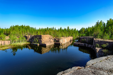 Obraz premium Blue pond formed at the bottom of the abandoned granite quarry.