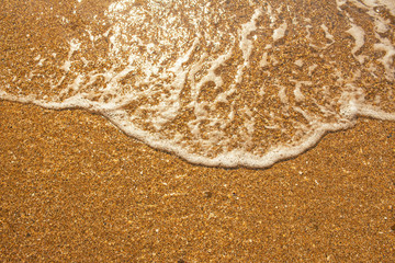 foaming sea wave rolls on the yellow sand