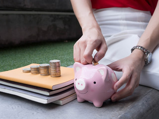 Woman Putting Coin In Piggy Bank.;