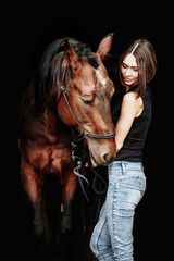 Fototapeta na wymiar Portrait of smiling pretty woman standing by horse on the black background. Isolate