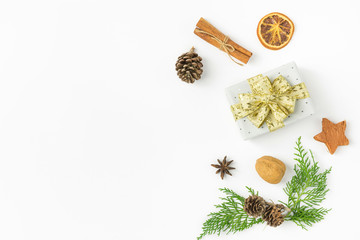 Fototapeta na wymiar Gift box wrapped in silver polka dot paper golden ribbon bow pine cones juniper nuts cinnamon on solid white background. New Year presents holiday preparations. Minimalist poster banner mockup