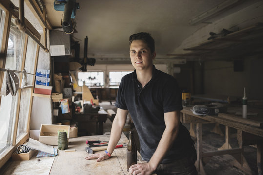 Portrait of smiling carpenter with bottle of beer in workshop