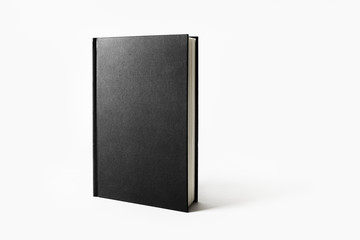 Mockup of closed blank black book on white paper background.