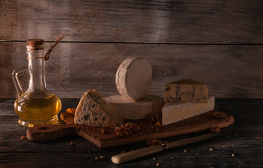 Obraz na płótnie Canvas Still life of different types of cheese and nuts, honey, wine. Posted on a wooden stand