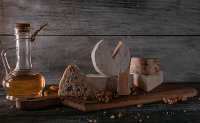 Still life of different types of cheese and nuts, honey, wine. Posted on a wooden stand