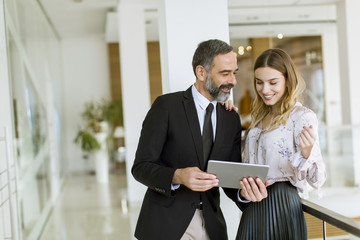 Young businesswoman and businessman look on digital tablet and discuss aout project