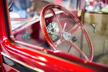 Detail of a red oldtimer car interior (steering wheel and the very simple dashboard) from outside