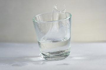 falling, flying or standing glass with a clear liquid intended for vodka and splash of liquid