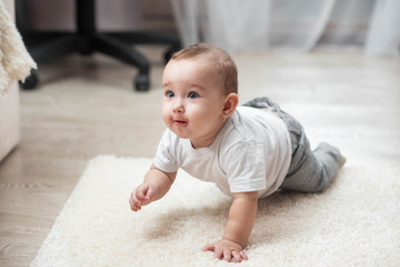 Smiling crawling baby boy at home on floor