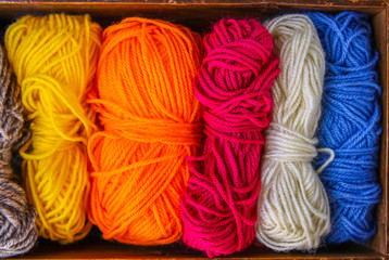 Colorful skeins of yarn in old wooden vintage box close up.