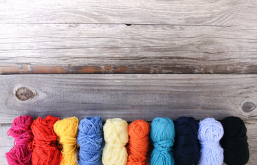 Colorful yarn skeins on rough wooden background.