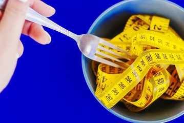The concept of the diet. The fork rewound centimeter lying on plate closeup