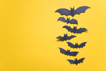 Halloween paper vampire bat decorations on an orange background.