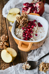 Breakfast: granola with pomegranate and walnuts and green Apple on natural wooden background rustic. The concept of healthy and high-carbon nutrition.