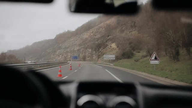 A car goes on highway in rain in the mountainous area. Working windshield wipers