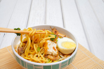 Malay Mee Rebus in the bowl  with chopsticks on white table This dish is made of noodles...