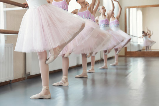 Girls training dance moves near ballet barre