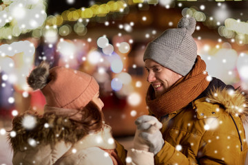 love, winter holidays and people concept - happy young couple dating and holding hands at christmas market in evening