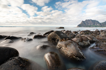 Long exposure of waves washing over rocks in Uttakleiv beach during day time. Lofoten, Norway.
