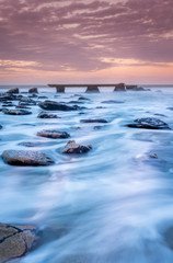 Atardecer en la costa con el agua fluyendo sobre las rocas