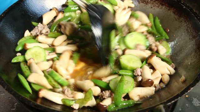 Frying mushroom with peanut and cucumber in pan
