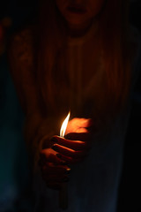 Candle in the hands of a girl in the dark