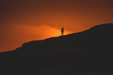 silhouette of man on top of mountain at sunset