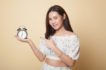 Young Asian woman point to a clock.