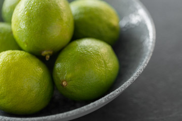 food, healthy eating and vegetarian concept - close up of whole limes in bowl