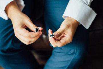 Close-up of a man in a tux fixing his vintage cufflink. groom bow tie cufflinks