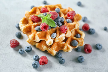 Delicious waffles with berries on grey table